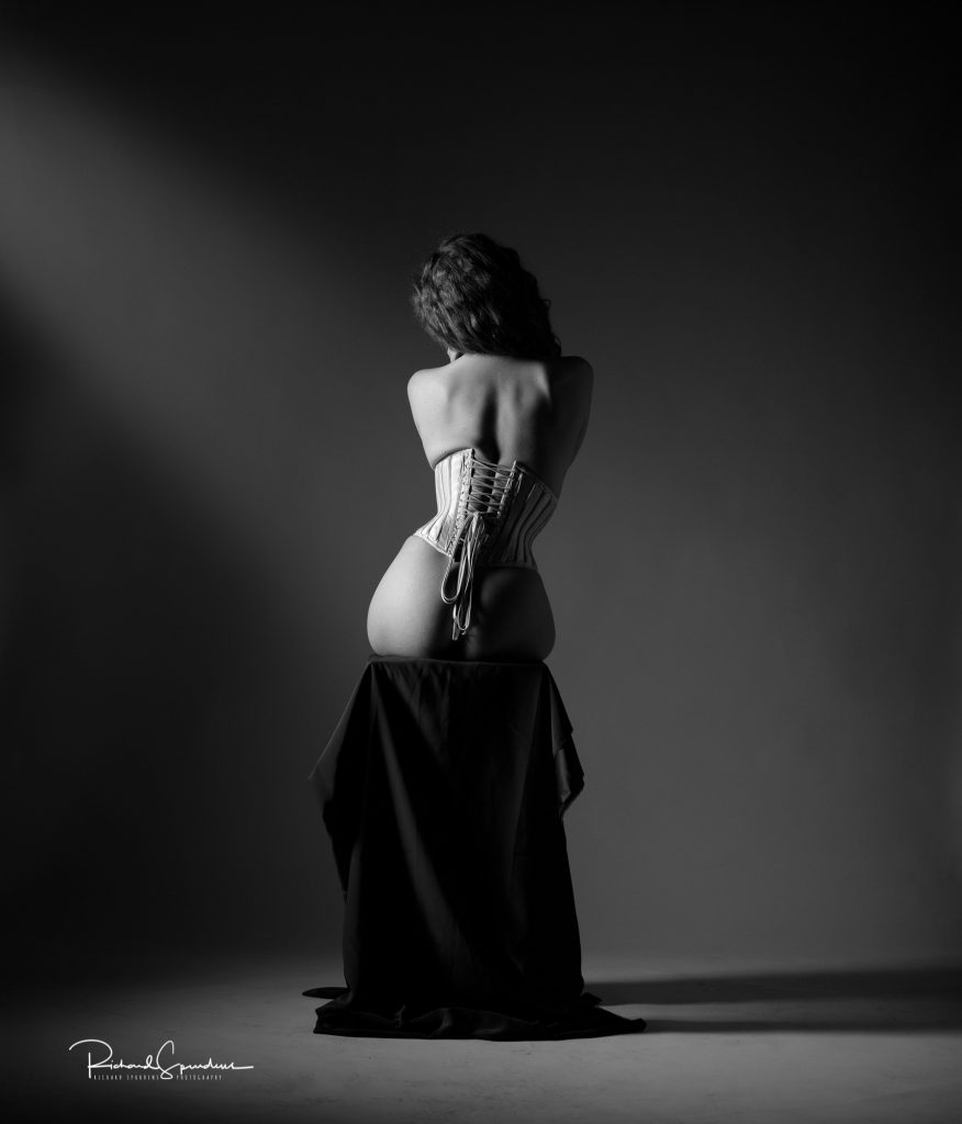 Artistic nude photographer - artistic nude photography - monochrome image using a single side light to illuminate the model fiqure and the corset she is wearing