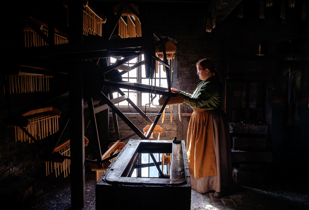travel Photography - travel Photograher - colour image taken a the victorian village a ironbridge interior shot of the candel maker workshop using the back window light showing the machine and candle maker at work in the gloom light of the workshop