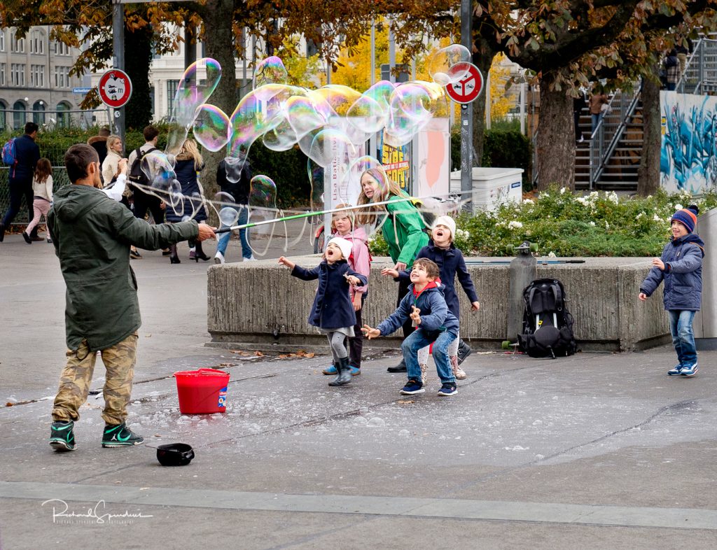 travel photography - travel photograher - images from a visit to zurich this featuring five children enjoying the fun of chasing large bubbles in a park