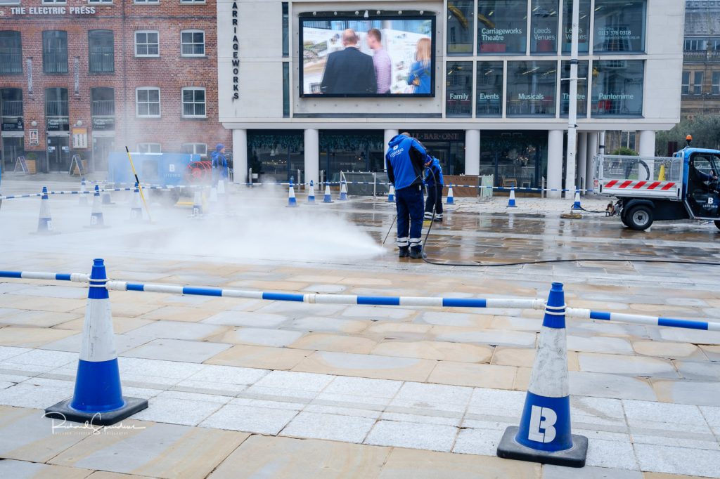image showing the leeds bid team using a steam cleaner of the paving stones in the millinumn square