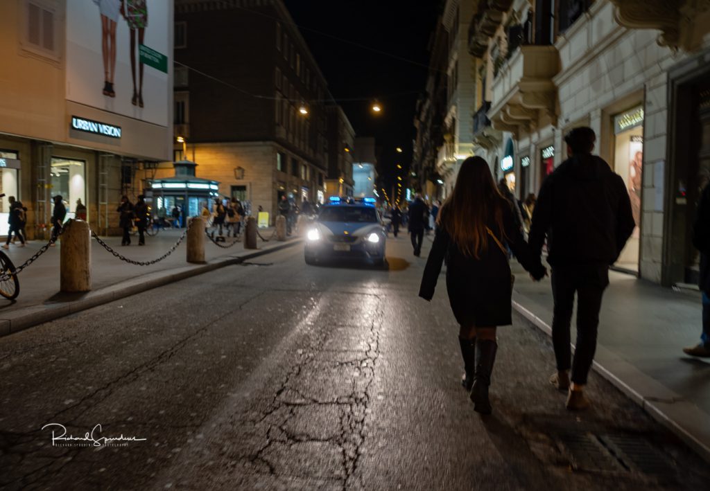 image from one of the main shopping streets showing a couple walking hand in hand against the on coming cars (februay images)