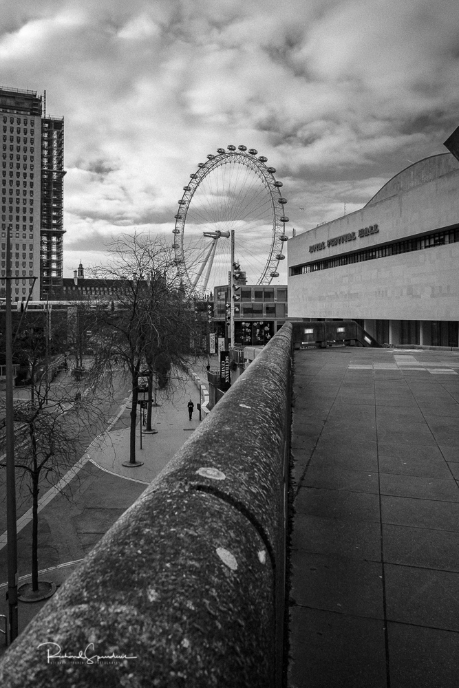 travel photography - travel photograher - images from a visit to london this one in monochrome using the lead the top of a wall to take you towards the royal festival hall and the london eye beyond it