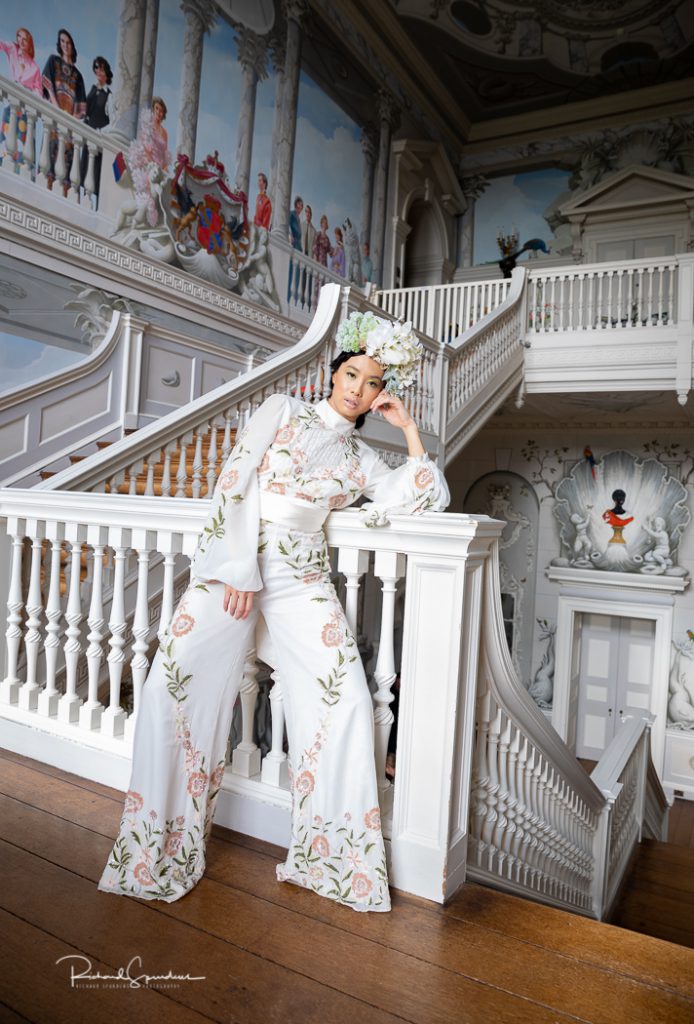 Fashion Photography - Fashion Photographer - an interior shot of the model wearing a white trouser suit and floral head piece in the white stair way