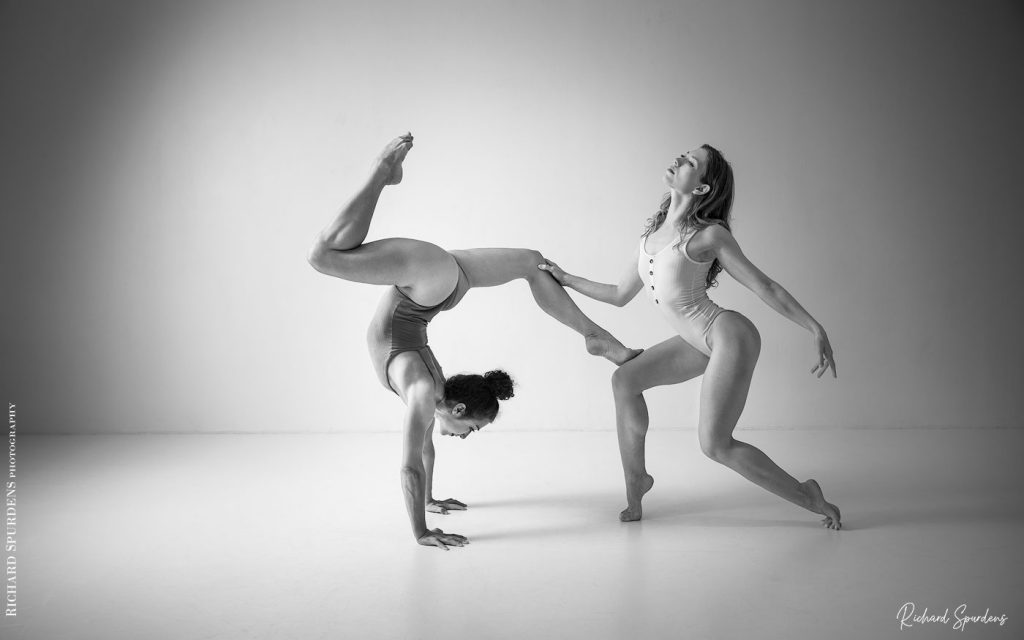 Dance Photographer - Dance photography -dancers poppyseed and jasmin who is holding a handstand with her legs at ninety degress and the second is holding her in balance