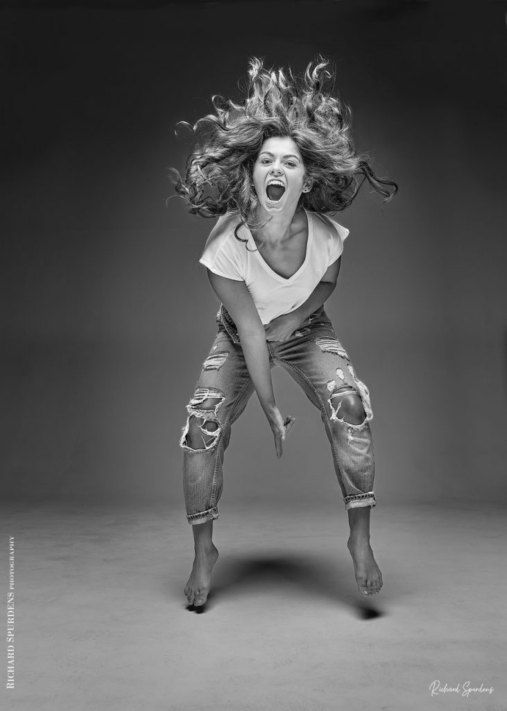Fashion Photography - Fashion Photographer - model wearing torn jeans jump off the floor with hair flowing up into the air