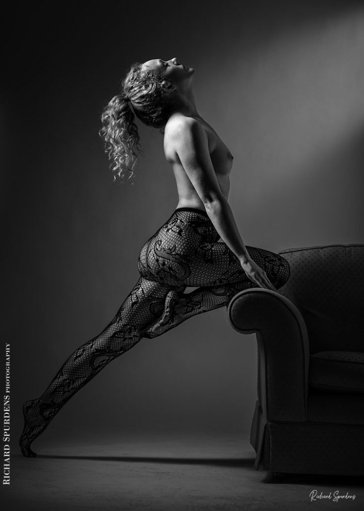 Fine Art Nude Photography - Nude Photography - Fine Art Nude Photographer - Ivory flame wearing paisley patterned tights and making strong female form shapes against the edge of a settee