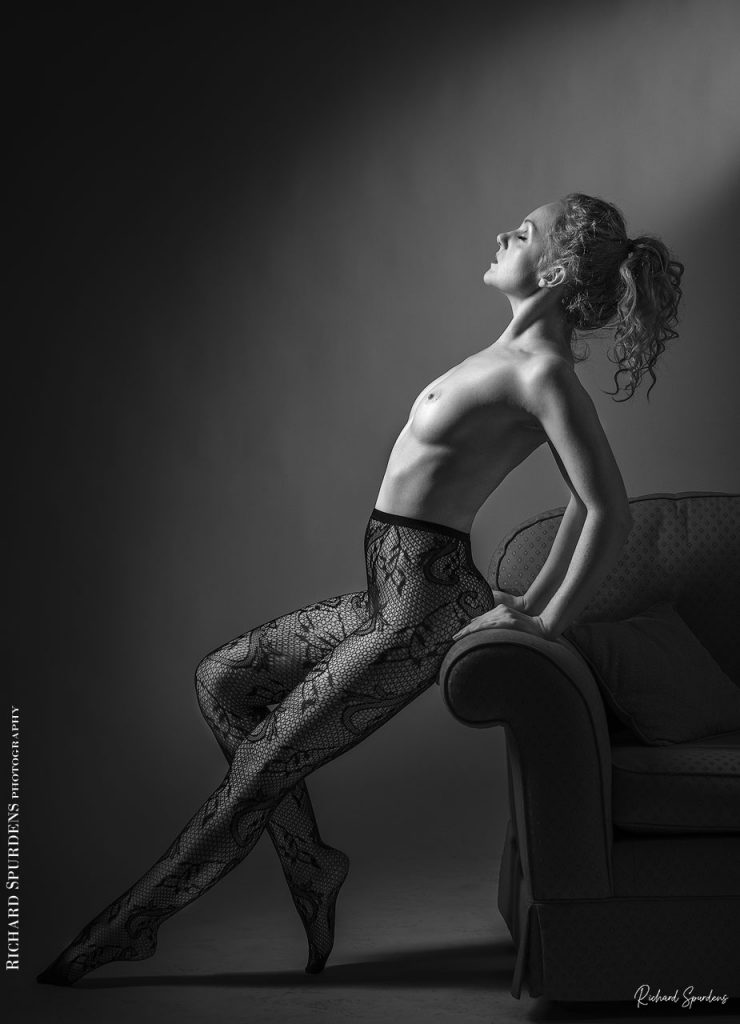 Fine Art Nude Photography - Nude Photography - Fine Art Nude Photographer - Ivory flame wearing paisley patterned tights and making strong female form shapes against the edge of a settee