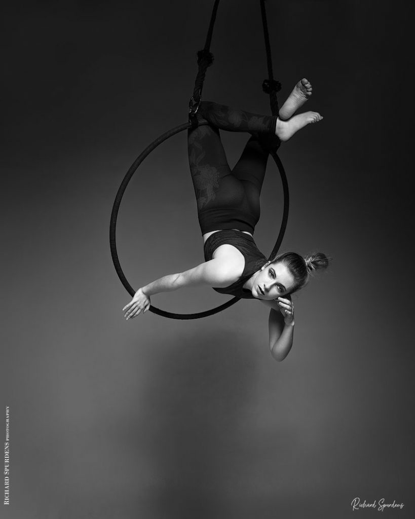 Aerial Arts photographer - Aerial hoop photographer - Aerial Arts photography - Aerial hoop photography - aerialist hanging from her hoop with her kness as the anchore