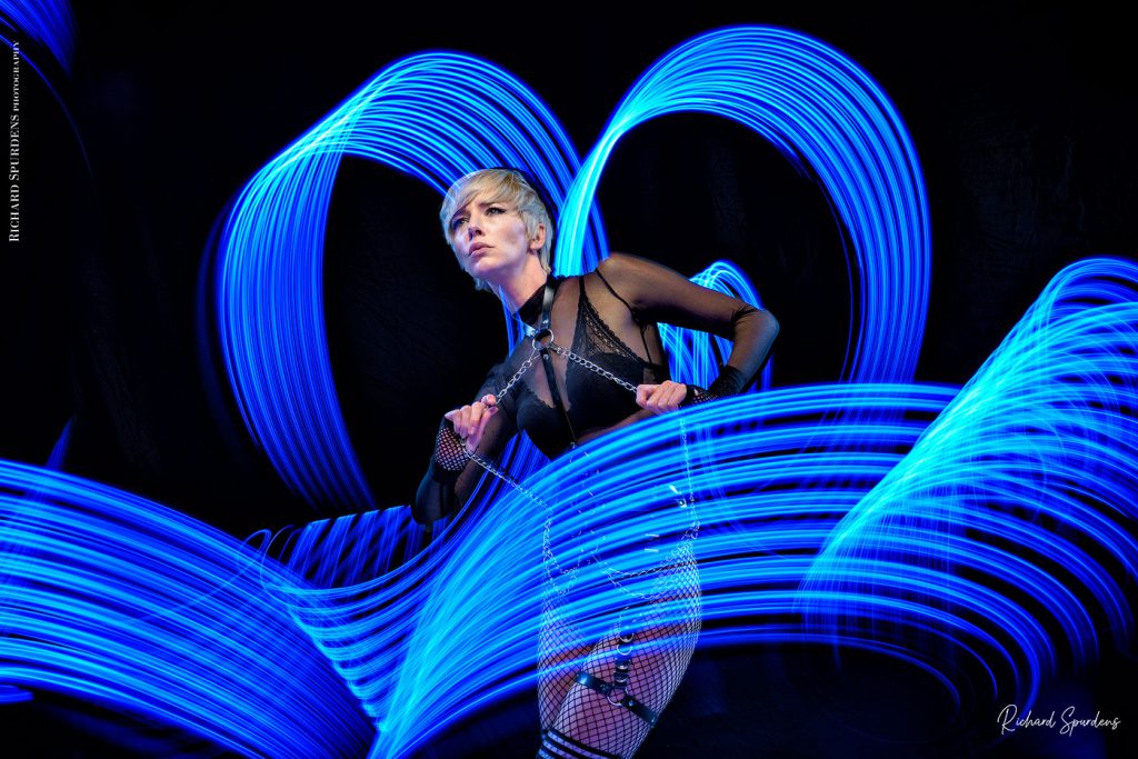 Light painting Photography - Fashion Photographer - colour image using a blue light painting wand creating blue swirls around the model